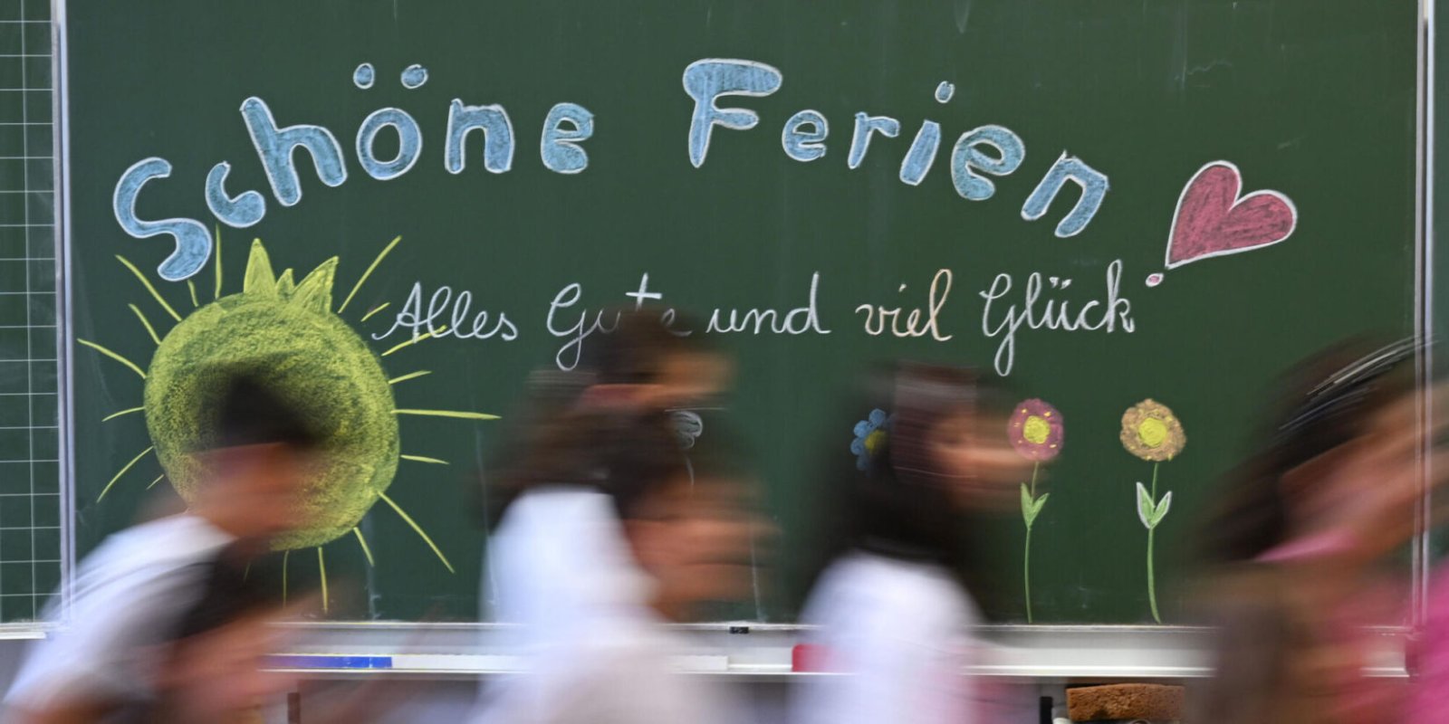 Zu Beginn der Herbstferien in NRW Schulkinder laufen an der Tafel vorbei.
