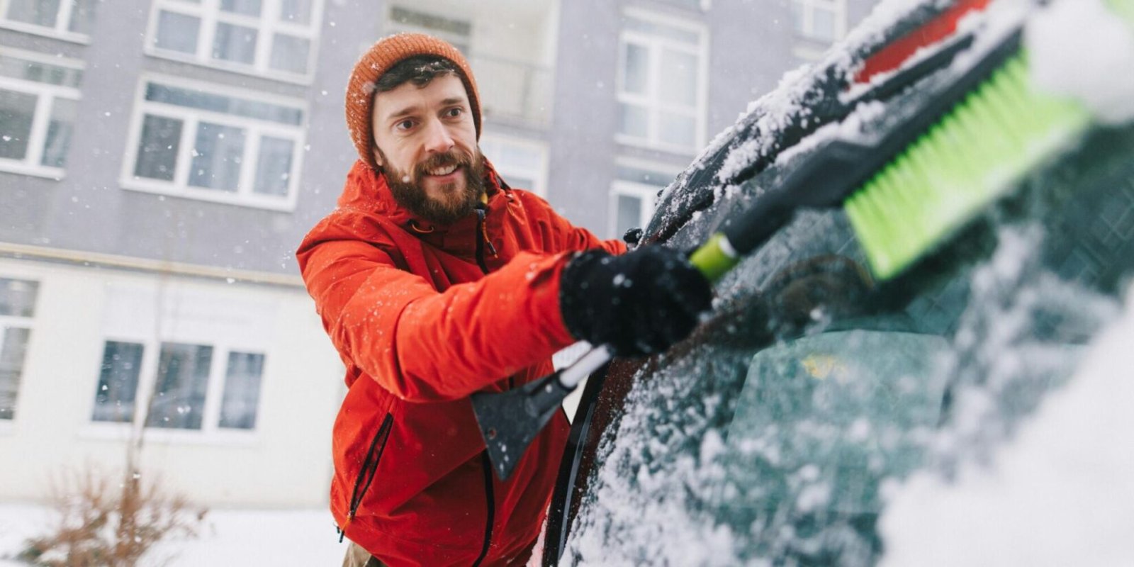 Ein Mann fegt Frost von einer Autoscheibe.