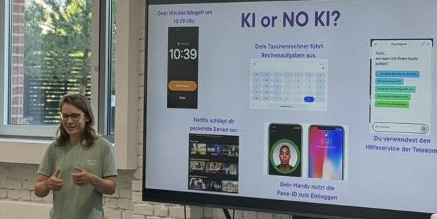 Eine Person steht in einer Unterrichtssituation/Präsentation vor einem Monitor. Darauf ist eine Folie mit der Überschrift "KI or NO KI?" zu sehen.© ifgi